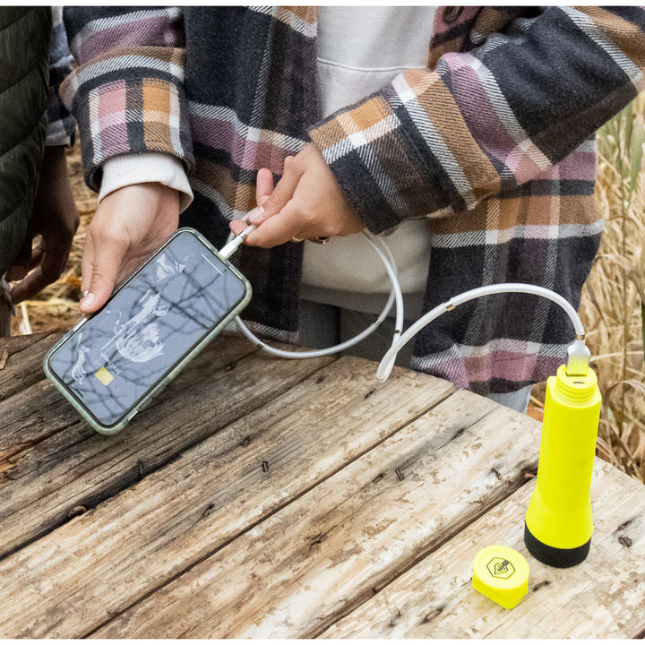 Journey 700 Solar Flashlight Yellow charging phone on table