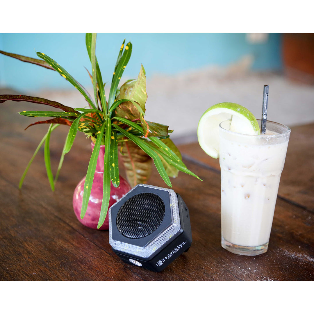 HEX Solar Speaker Charger on table with drink